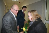 Komendant Miejski Policji w Chorzowie wraz ze swoim zastępcą wręczają kwiaty kobietom wchodzącym do Komendy.