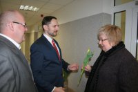 Komendant Miejski Policji w Chorzowie wraz ze swoim zastępcą wręczają kwiaty kobietom wchodzącym do Komendy.