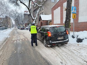 Zdjęcie przedstawia policjanta oraz strażnika miejskiego podczas kontroli pojazdu